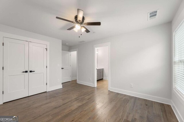 unfurnished bedroom featuring a closet, ceiling fan, dark wood-type flooring, and ensuite bathroom