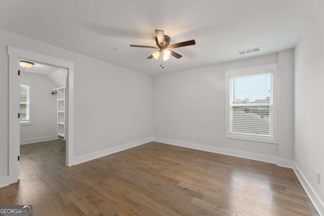 unfurnished room with a wealth of natural light, dark hardwood / wood-style flooring, and ceiling fan