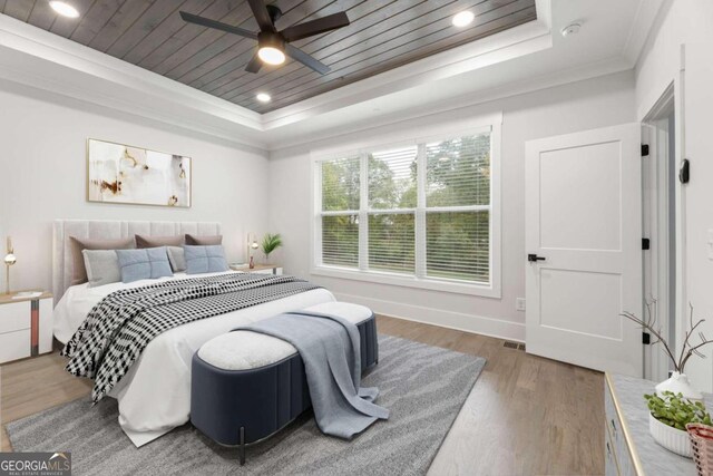 bedroom with hardwood / wood-style floors, wooden ceiling, crown molding, ceiling fan, and a tray ceiling