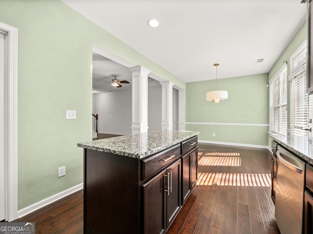 kitchen with pendant lighting, dark wood-type flooring, stainless steel dishwasher, ornate columns, and a kitchen island