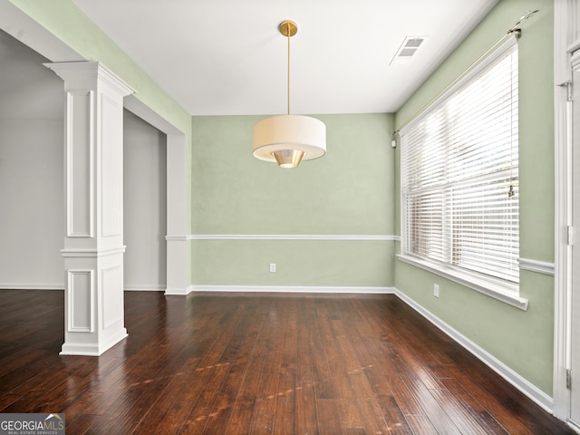 unfurnished dining area featuring ornate columns and dark hardwood / wood-style flooring