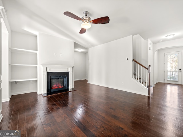 unfurnished living room with dark hardwood / wood-style flooring, built in features, and ceiling fan