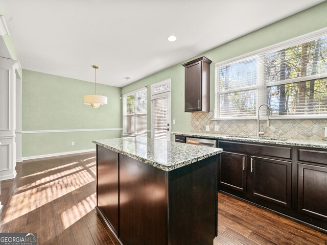 kitchen with dark brown cabinets, a kitchen island, dark wood-type flooring, and decorative light fixtures