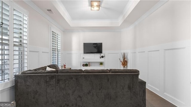 living room with a tray ceiling, a wealth of natural light, dark hardwood / wood-style flooring, and ornamental molding