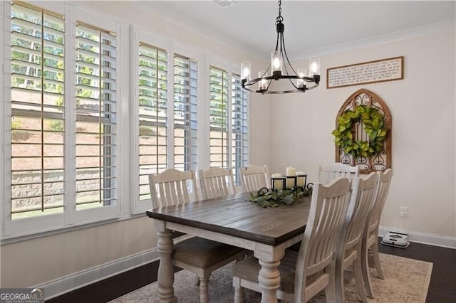 dining space with dark hardwood / wood-style floors, crown molding, and a chandelier