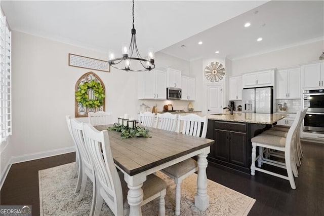 dining area featuring dark hardwood / wood-style flooring, ornamental molding, sink, and a chandelier