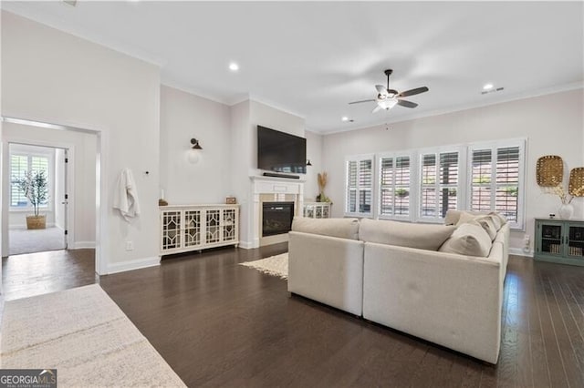 living room with dark hardwood / wood-style floors, ceiling fan, and crown molding