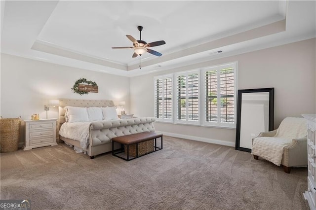 carpeted bedroom featuring a tray ceiling and ceiling fan