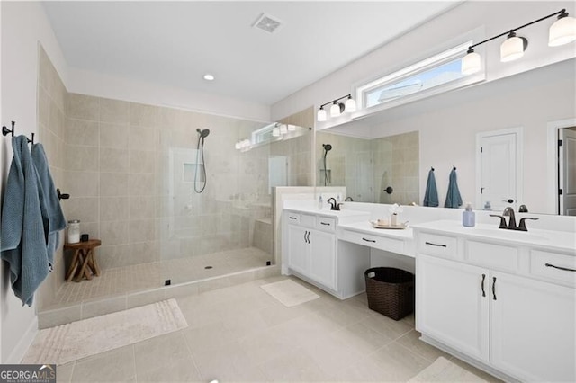 bathroom with a tile shower, tile patterned flooring, and vanity