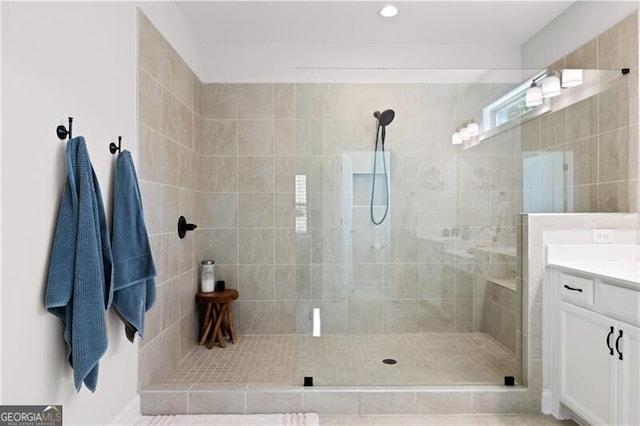 bathroom with a tile shower and vanity