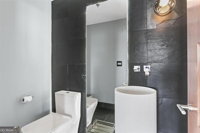 bathroom featuring tile patterned flooring, tile walls, and toilet