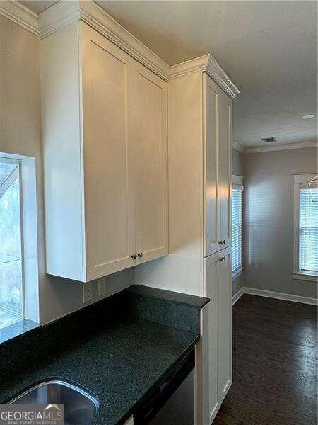 kitchen featuring sink, white cabinetry, dark wood-type flooring, and ornamental molding