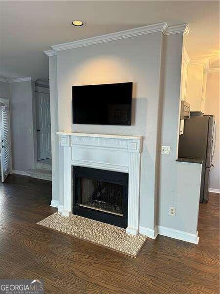 interior details featuring stainless steel refrigerator, crown molding, and hardwood / wood-style flooring