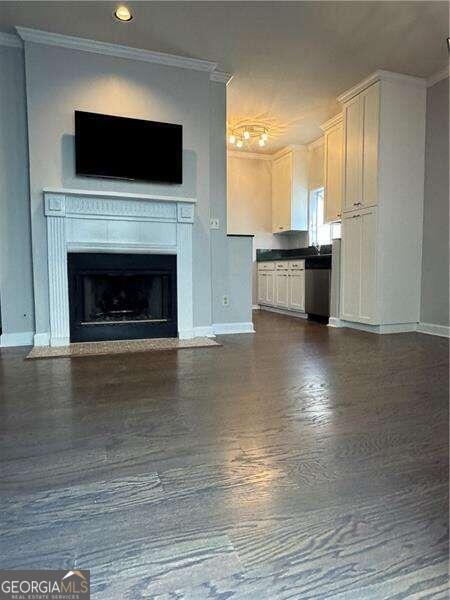 unfurnished living room featuring dark hardwood / wood-style flooring and crown molding