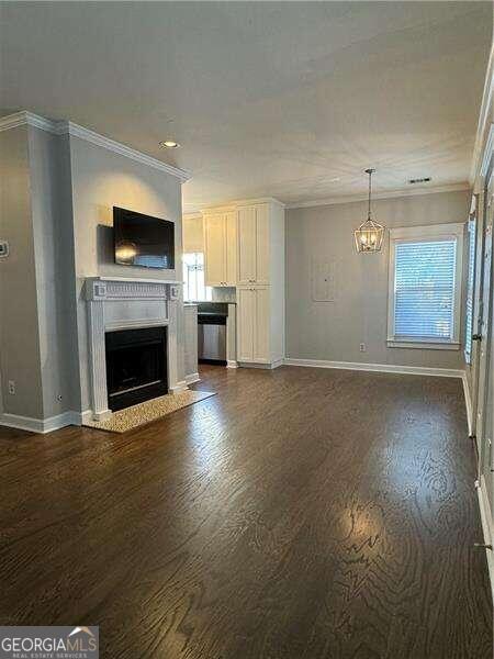 unfurnished living room with dark hardwood / wood-style floors, a wealth of natural light, and crown molding