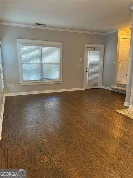 unfurnished living room featuring dark hardwood / wood-style floors and ornamental molding