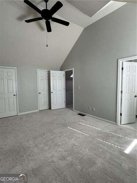 unfurnished bedroom with ceiling fan, high vaulted ceiling, and light carpet