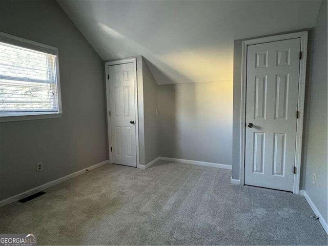 additional living space with light carpet and vaulted ceiling