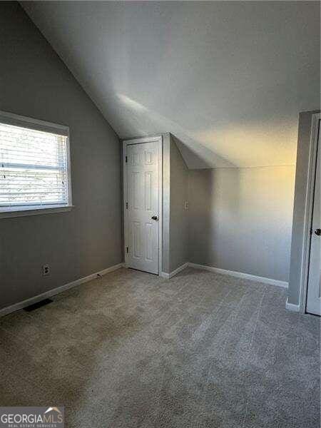 additional living space featuring carpet flooring and vaulted ceiling