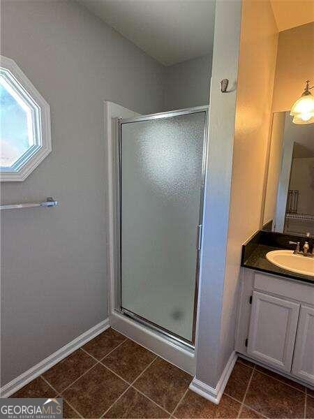 bathroom with tile patterned flooring, vanity, and a shower with shower door