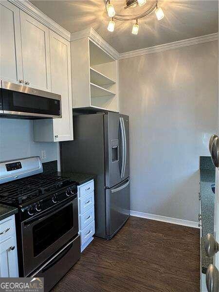 kitchen featuring appliances with stainless steel finishes, dark hardwood / wood-style floors, white cabinetry, and crown molding