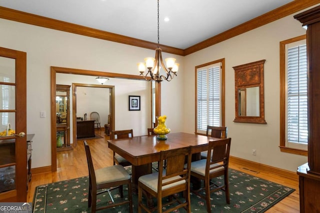 dining area with light hardwood / wood-style flooring, an inviting chandelier, and ornamental molding