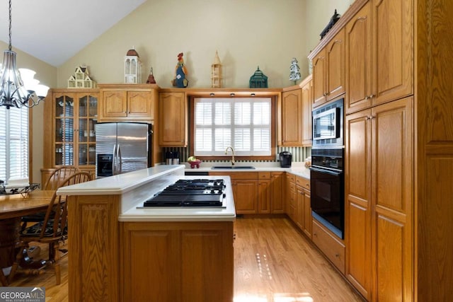 kitchen featuring a center island, sink, stainless steel appliances, pendant lighting, and light wood-type flooring