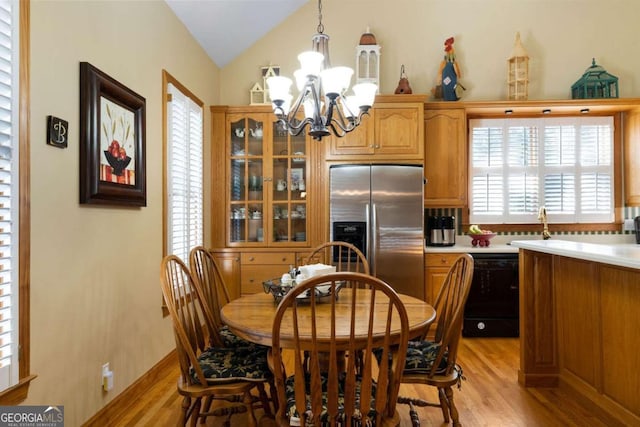 dining area with lofted ceiling, light wood-type flooring, and a notable chandelier