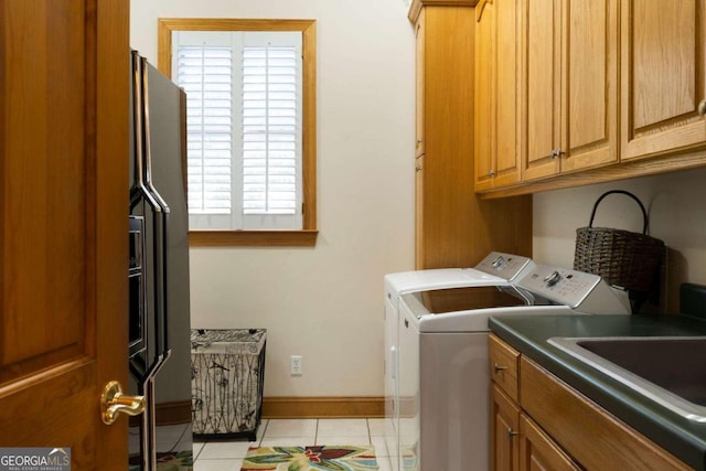 laundry room featuring washing machine and clothes dryer, light tile patterned floors, and cabinets