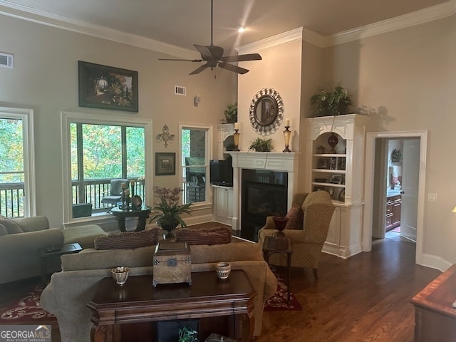 living room featuring plenty of natural light, ceiling fan, crown molding, and dark wood-type flooring