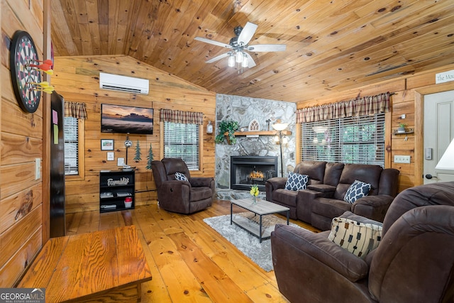 living room with wooden walls, light hardwood / wood-style flooring, a wall mounted air conditioner, wood ceiling, and a stone fireplace