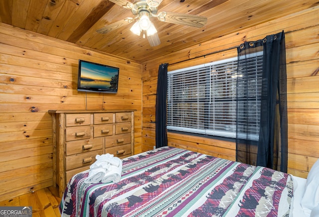 bedroom with ceiling fan, wood ceiling, and wood walls