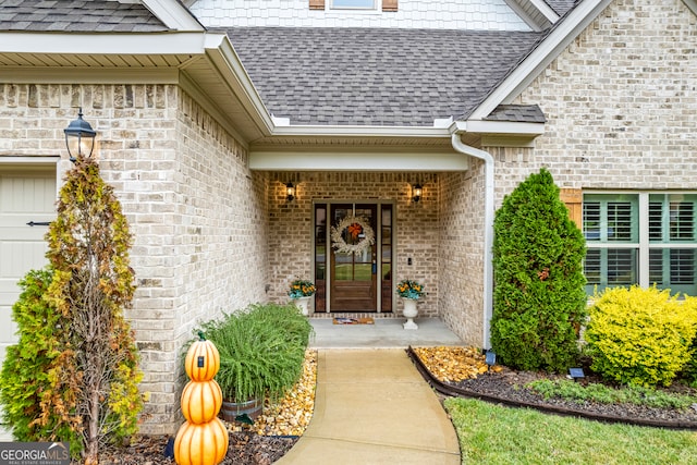 entrance to property featuring a shingled roof, covered porch, brick siding, and an attached garage