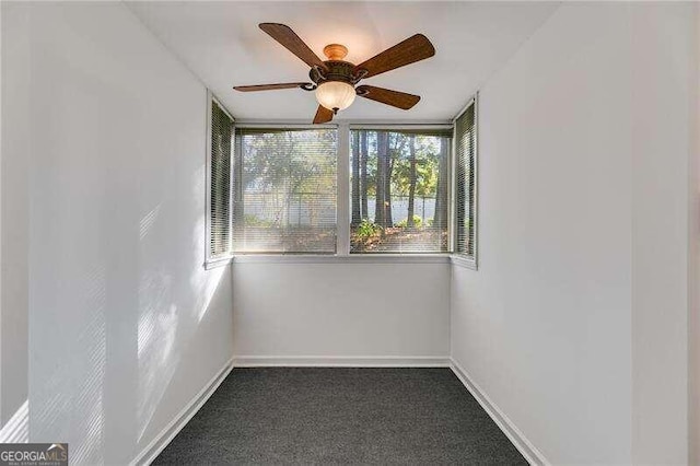 empty room with dark colored carpet and ceiling fan