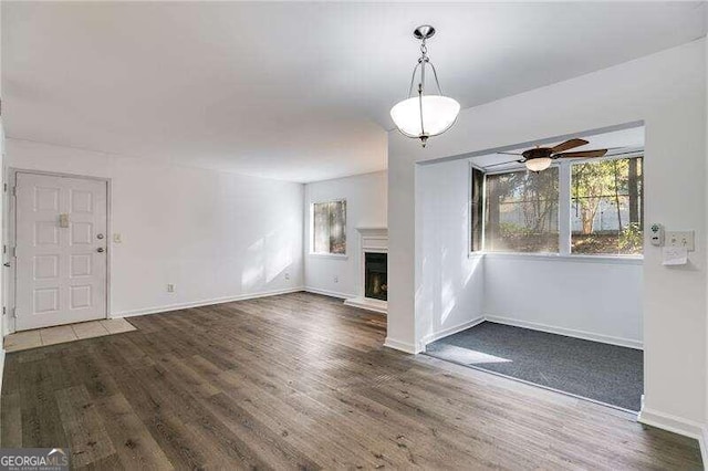 unfurnished living room featuring ceiling fan and dark hardwood / wood-style flooring