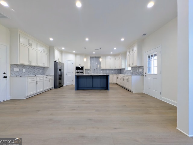 kitchen with stainless steel refrigerator with ice dispenser, backsplash, decorative light fixtures, a center island, and light hardwood / wood-style floors