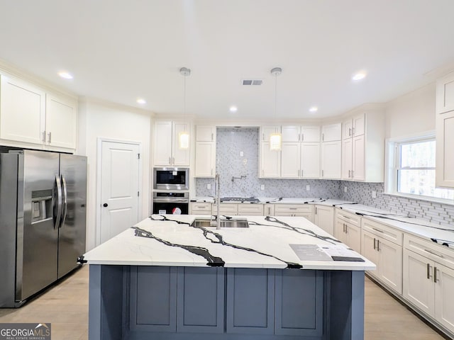 kitchen with light stone countertops, a kitchen island with sink, hanging light fixtures, and appliances with stainless steel finishes