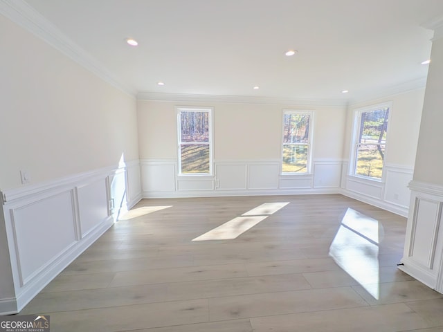 unfurnished room with decorative columns, crown molding, and light hardwood / wood-style floors