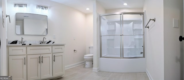 full bathroom with vanity, bath / shower combo with glass door, and toilet