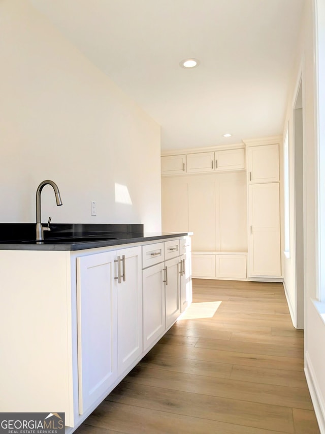 kitchen with light hardwood / wood-style flooring, white cabinetry, and sink