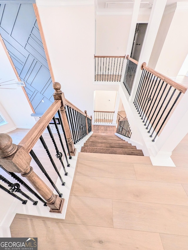 stairway with a towering ceiling and crown molding