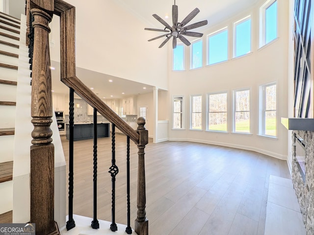 stairway with ornate columns, ceiling fan, a high ceiling, and hardwood / wood-style flooring