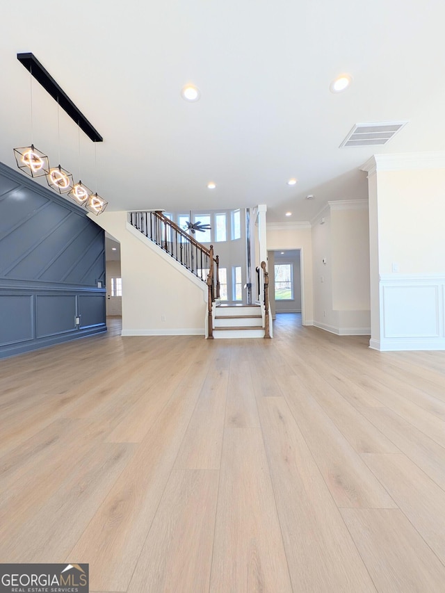 unfurnished living room featuring crown molding and light wood-type flooring