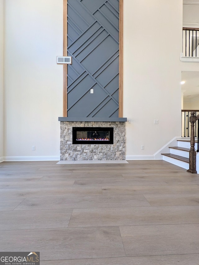 unfurnished living room with a stone fireplace and light hardwood / wood-style floors