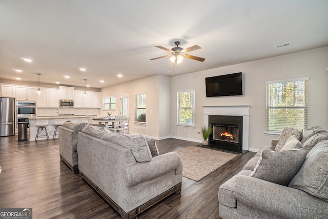 living room with ceiling fan and dark wood-type flooring