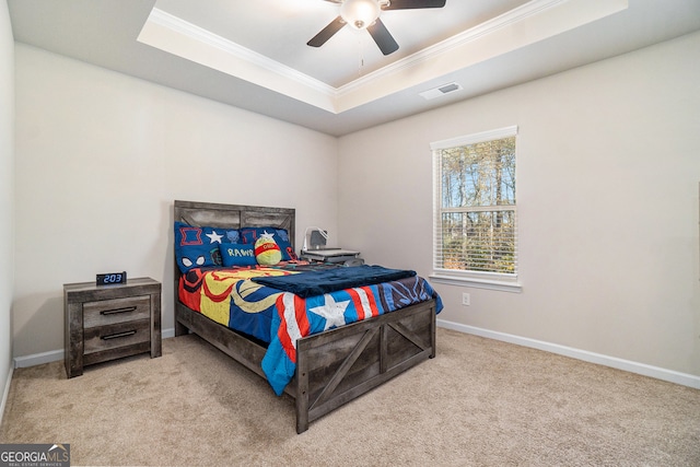 carpeted bedroom featuring ceiling fan, crown molding, and a tray ceiling