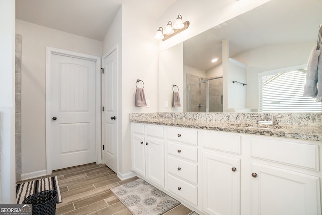 bathroom with a shower with door, vanity, wood-type flooring, and lofted ceiling