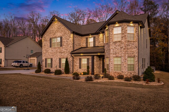 view of front of home with a lawn, central AC, and a garage