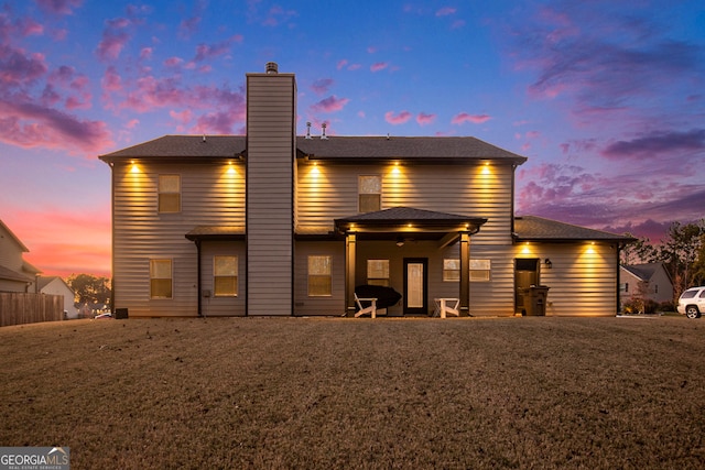 back house at dusk featuring a yard