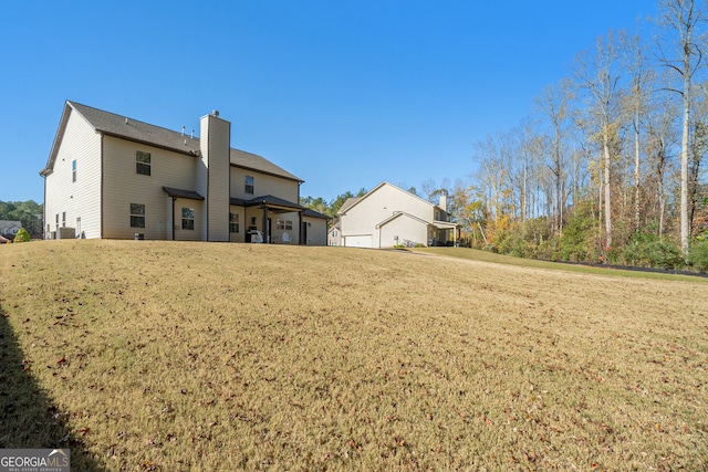 rear view of property featuring a garage and a yard